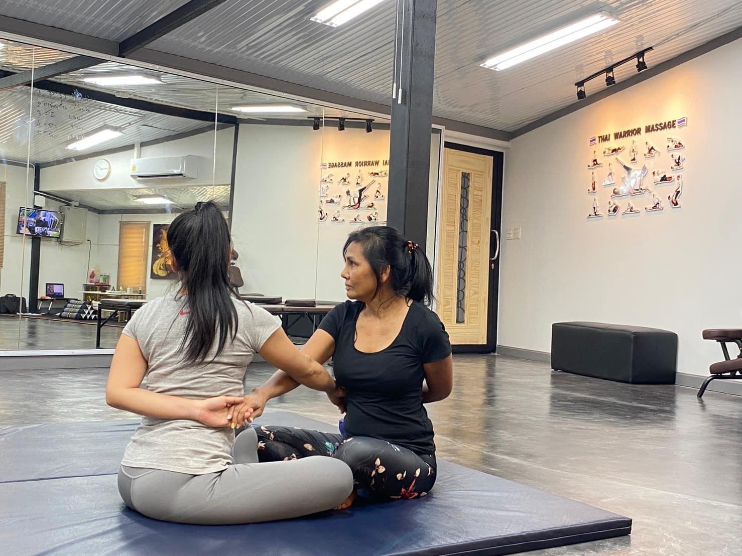 Ninlaya unterrichtet Thai-Massage: sie führt die Hände einer Schülerin